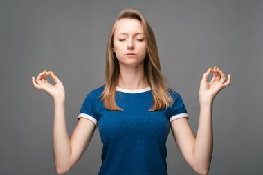 Genç, güzel sarışın kadın meditasyon yapıyor, gözleri kapalı, uzun saatler çalıştıktan sonra dinlenmeye çalışıyor, parmaklarını yoga işaretinde tutuyor. Rahatlama kavramı