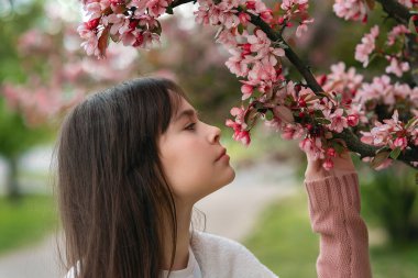 Çiçek açan pembe ağacın altında 11-12 yaş arası güzel esmer kız. Moda konsepti