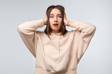 Uzun kestane rengi saçları olan, günlük kıyafetler giymiş kulakları beyaz arka planda olan güzel bir kadın. İnsani duygular, sessizlik konsepti