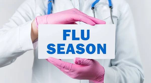 코트와 분홍색 장갑을 의사가 텍스트 Flu Season 카드를 모습이 띄었다 — 스톡 사진