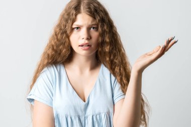 What the hell are you talking about, nonsense. Studio shot of frustrated female with curly long hairstyle gesturing with raised palm, frowning, being displeased and confused with dumb question.