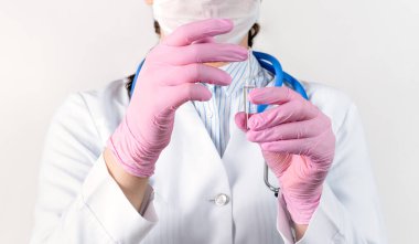 Beyaz önlüklü, tıbbi maskeli ve pembe steril eldivenli, ampul aşılı genç bir kadın doktor görüntüsü. Kavram: hastalıklar, tıbbi bakım, bilim