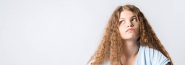 Dalgın Avrupalı, uzun kıvırcık saçlı genç bir kadının fotoğrafı. Düşünceli bir ifadeyle yukarı bakıyor. Beyaz arka planda izole edilmiş. Metnin için boşluk kopyala