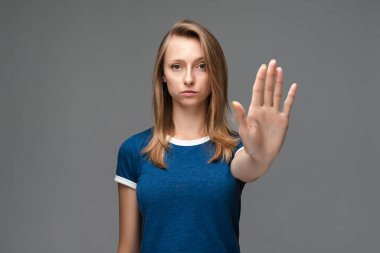 Mavi tişörtlü, sarı düz saçlı ciddi bir kız elinde bir dur işareti yapıyor. Bitişi, reddedilme sembolü gösteriyor. Şiddete izin vermiyor..