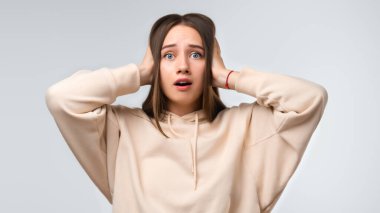 Uzun kestane rengi saçları olan, günlük kıyafetler giymiş kulakları beyaz arka planda olan güzel bir kadın. İnsani duygular, sessizlik konsepti