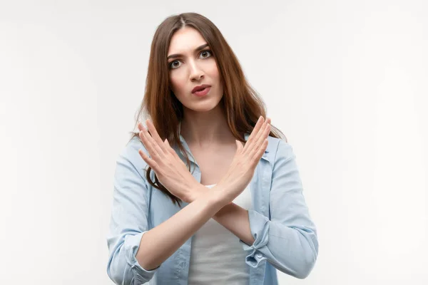 Uzun kestane rengi saçları olan ciddi bir kız, günlük kıyafetler giymiş, jest yapıp duruyor, bitiriyor, reddedilmenin sembolü, şiddete, vücut diline izin vermiyor. İnsani duygular, yüz ifadesi kavramı.