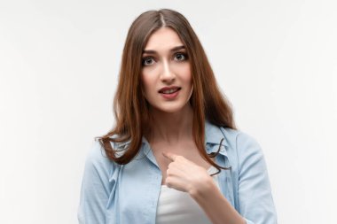 Uzun düz saçlı kızgın esmer bir kadının fotoğrafı, kendini parmağıyla gösteriyor, şaşırarak ağzını açıyor, tatminsiz bir ifade sergiliyor, kırıcı sözlerle boğuşuyor..