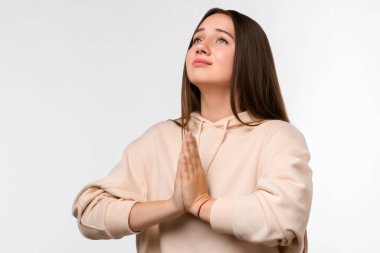 Uzun saçlı, mutlu esmer bir kadının resmi. Gülümseyen ve avuçlarını bir arada tutan sıradan kıyafetler giymiş bir kadın. Meditasyon yapıyor, barış ve sevgi için dua ediyor, sakin ve huzurlu bir yüz ifadesi var.