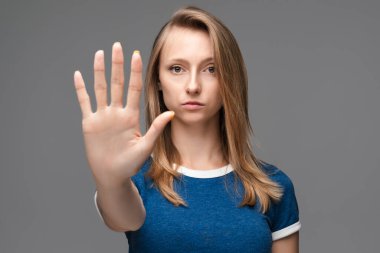 Mavi tişörtlü, sarı düz saçlı ciddi bir kız elinde bir dur işareti yapıyor. Bitişi, reddedilme sembolü gösteriyor. Şiddete izin vermiyor..