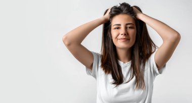 Kafasında uzun kestane rengi saçları olan ya da saçlarına dokunan tasasız, modern bir kız. Beyaz arka planda izole edilmiş. Duygular, ifadeler, saç stili ve insanlar konsepti.