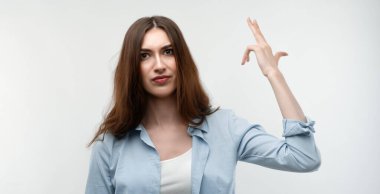 Uzun kestane rengi saçları olan, sıradan kıyafetler giyen, silah atışı taklidi yapan, mutsuz, beyaz bir kadın intihar jesti yapıyor, iki parmağını şakakta tutuyor, kafası karışık bir ifade takınıyor. İnsan duyguları kavramı.