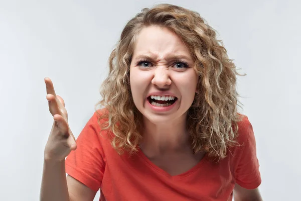 怒り狂ったブロンドの女性が怒りで叫び 手を上げるカジュアルなTシャツに巻き毛を持つ 憎しみ 否定的な感情 顔の表情の概念 スタジオショット 白い背景 隔離された — ストック写真