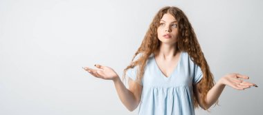 Sorun ne? Kafası karışmış, uzun kıvırcık saçlı güzel bir kızın portresi, ellerini yana açıyor, sırıtıyor, seçimler yaparken şüpheye düşüyor, gündelik tişört giyiyor. Beyaz arkaplanda izole.