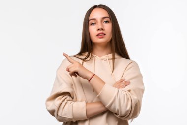 Uzun kestane rengi saçları olan mutlu, genç bir kadın, bir tarafı işaret ediyor, bilgi için kopyalama alanı gösteriyor. Stüdyo çekimleri beyaz arkaplan