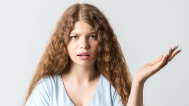 What the hell are you talking about, nonsense. Studio shot of frustrated female with curly long hairstyle gesturing with raised palm, frowning, being displeased and confused with dumb question.