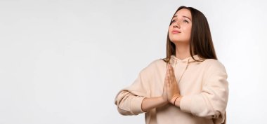 Uzun saçlı, mutlu esmer bir kadının resmi. Gülümseyen ve avuçlarını bir arada tutan sıradan kıyafetler giymiş bir kadın. Meditasyon yapıyor, barış ve sevgi için dua ediyor, sakin ve huzurlu bir yüz ifadesi var.