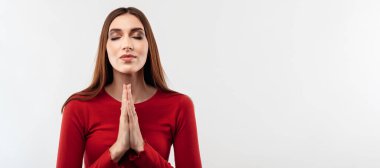 Uzun saçlı, sıradan kırmızı kazaklı neşeli esmer kadının portresi avuç içlerini birleştirip dua ediyor. Meditasyon yapıyor, barış ve sevgi için dua ediyor, sakin ve huzurlu bir yüz ifadesi var.