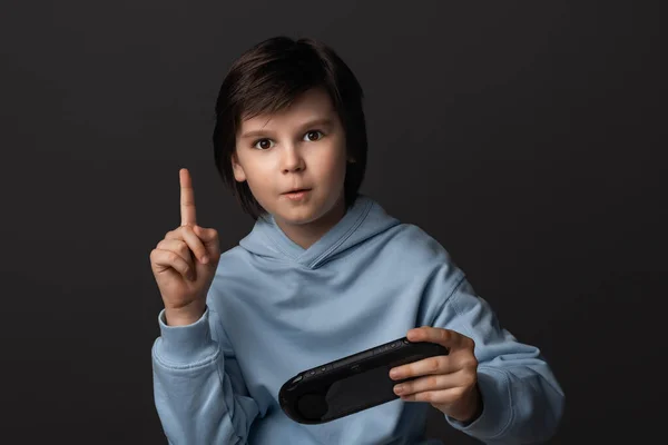 可爱男孩的肖像 12岁 穿着休闲装 手拿着游戏垫 玩电子游戏 面部表情的概念 工作室拍摄 灰色背景 — 图库照片