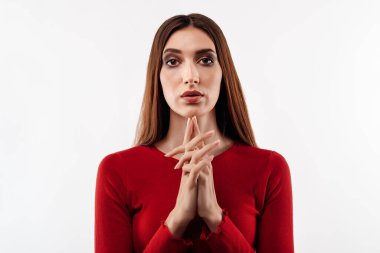 Uzun kestane rengi saçlı, düşünen, kameraya bakıp ellerini çenesine yakın tutan, sıradan kırmızı kazak giyen hoş bir kadın resmi. İnsani duygular, yüz ifadesi kavramı