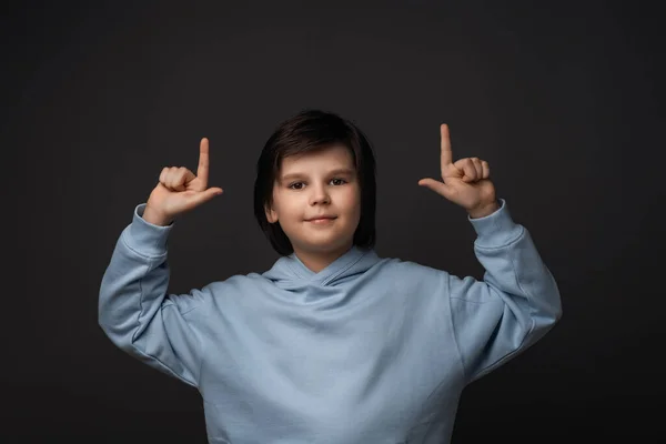 かわいい男の子の肖像10 12歳のカジュアルな服で彼の人差し指で指して あなたの情報のためのコピースペースを示しています スタジオ撮影 グレーの背景 人間の感情や表情の概念 — ストック写真