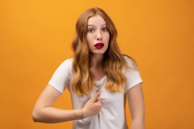 Beyaz tişörtlü, öfkeli bir kadının fotoğrafı kendini parmağıyla işaret ediyor, ağzı açık, tatmin olmamış bir ifade sergiliyor, kırıcı sözlerle ürküyor.