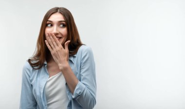 Uzun kestane rengi saçlı, günlük kıyafetler giymiş, kıkırdayan ve eliyle ağzını kapatan karizmatik beyaz kız. İnsani duygular, yüz ifadesi kavramı. Metnin için boşluk kopyala