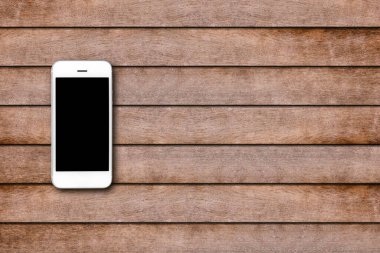 Ahşap masa arkasında boş ekranlı cep telefonu. Eski ahşap döşeme kumaş arka planında akıllı telefon. Üst görünüm, boşluk kopyala