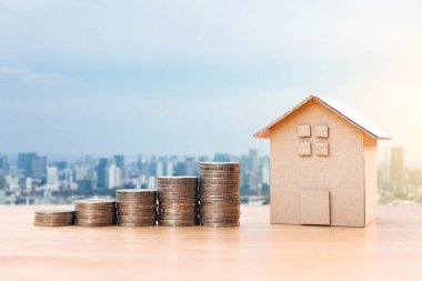 Coins money and house model on wooden table for finance and banking. Concept for property ladder, mortgage and real estate investment .Investment and saving concept
