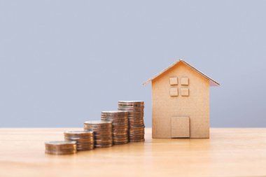Coins money and house model on wooden table for finance and banking. Concept for property ladder, mortgage and real estate investment .Investment and saving concept