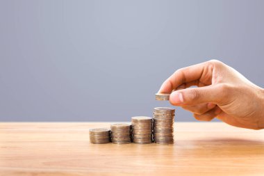 Hand putting money coins on row of coin money for finance and banking. Concept for property ladder, mortgage and real estate investment .Investment and saving concept