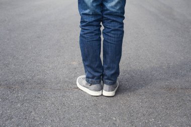 Little kid traveller standing on the road. Close up legs of boy standing on asphalt road in park morning. childhood, learning, leisure and people concept