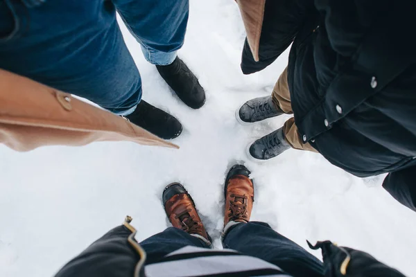 Legs of family with leather shoes. Looked shoes standing on the snow in winter. leisure and family travel concept. Top view