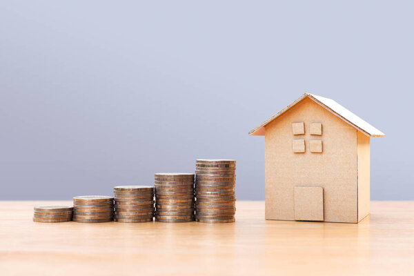 Coins money and house model on wooden table for finance and banking. Concept for property ladder, mortgage and real estate investment .Investment and saving concept