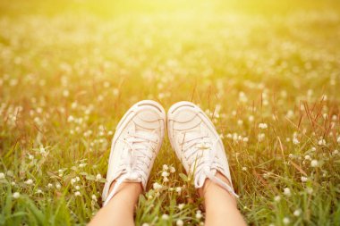 Parkta beyaz çiçekli, çimlerin üzerinde beyaz ayakkabılar. Yalnız seyahat kavramı