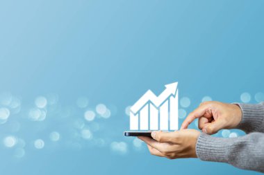 Elinde oklar olan bir adam cep telefonu tutarak grafiği büyüme ve başarının sembolü olarak veya gelecekte başarılı gelişim ve iş gelişiminin artışı olarak gösteriyor.
