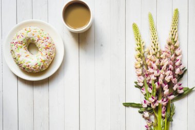 Bir fincan kahve ve acı bakla ile natürmort çörek ahşap masa lambası kopya alanı üzerinde çiçekler
