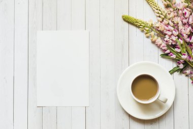 Bir fincan kahve ve acı bakla çiçekler üzerinde ahşap masa lambası kopya alanı ile natürmort