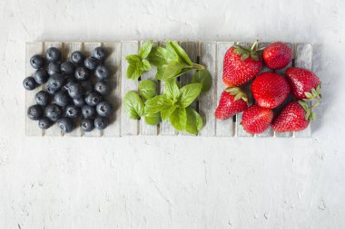 Taze çilek çilek yaban mersini nane kopya alanı metin için bir ahşap stand, gri zemin üzerine.