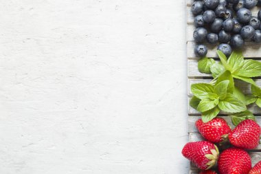 Taze çilek çilek yaban mersini nane kopya alanı metin için bir ahşap stand, gri zemin üzerine.