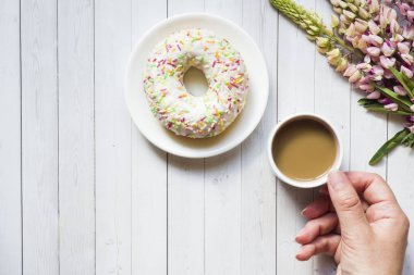 Bir fincan kahve ve acı bakla ile natürmort çörek ahşap masa lambası kopya alanı üzerinde çiçekler