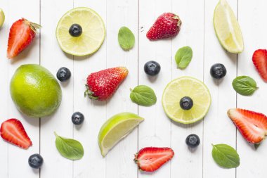 Narenciye kireç taze çilek, yaban mersini hafif bir arka plan üzerinde çilek nane. Düz yatıyordu yaz.