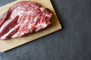 Ahşap kesme tahtası koyu arka plan üzerinde kırmızı ham sığır et parçası. Kopya alanı