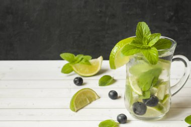 Serinletici içecekler limonata yaz ya da kireç taze nane yaban mersini buzla kokteyl Mojito. Masa lambası, karanlık duvar.