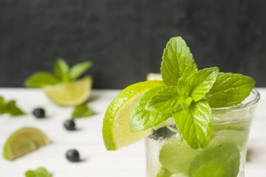 Serinletici içecekler limonata yaz ya da kireç taze nane yaban mersini buzla kokteyl Mojito. Masa lambası, karanlık duvar.