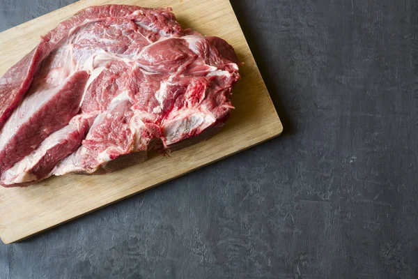 Ahşap kesme tahtası koyu arka plan üzerinde kırmızı ham sığır et parçası. Kopya alanı