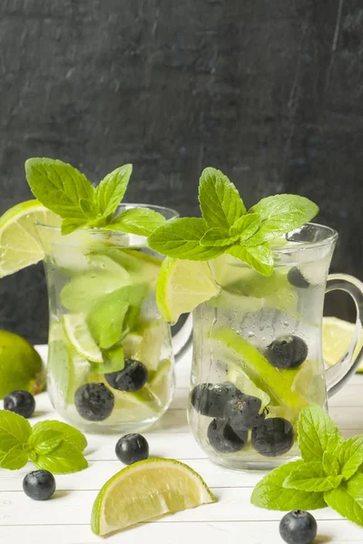 Serinletici içecekler limonata yaz ya da kireç taze nane yaban mersini buzla kokteyl Mojito. Masa lambası, karanlık duvar.