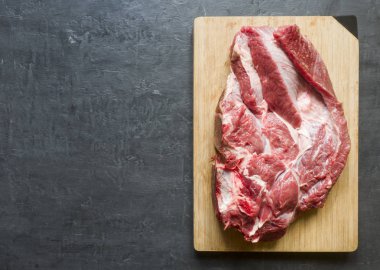 Ahşap kesme tahtası koyu arka plan üzerinde kırmızı ham sığır et parçası. Kopya alanı