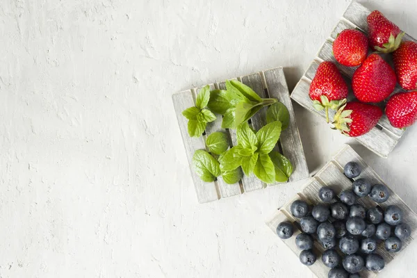 Taze çilek çilek yaban mersini nane kopya alanı metin için bir ahşap stand, gri zemin üzerine.