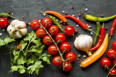 Sıcak biber çok renkli, şube, sarımsak ve diğer baharatlar siyah arka plan üzerine kiraz domates.