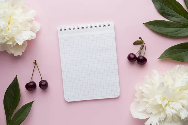 Notepad for text white flowers peony cherry berries on pastel pink background